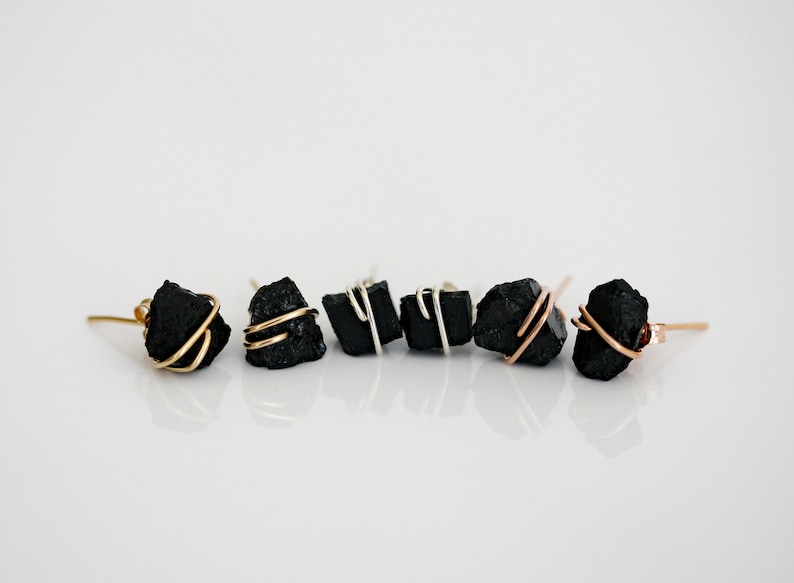 May include: A set of six black stone earrings with gold and silver wire accents. The earrings are all different shapes and sizes.