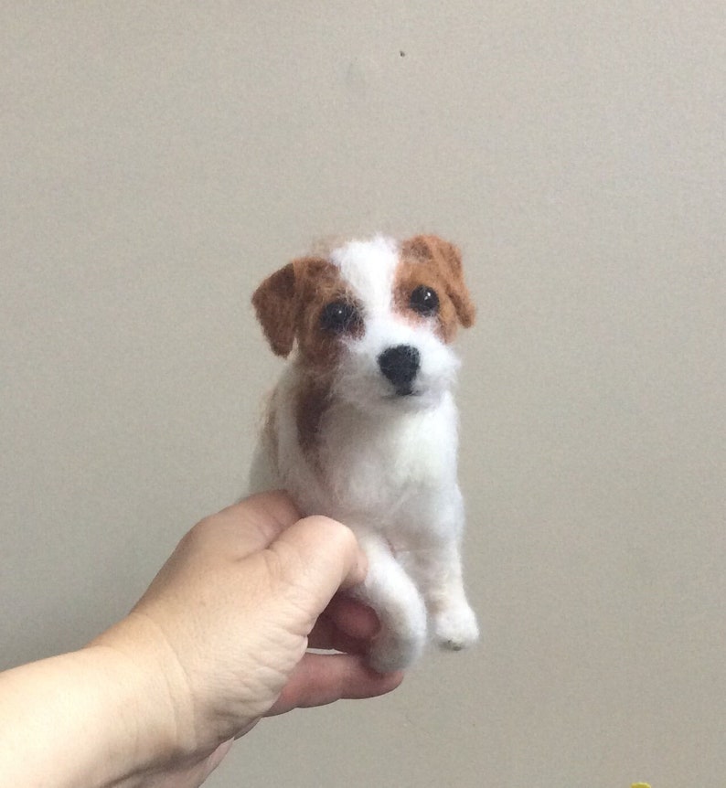 May include: A needle felted Jack Russell Terrier dog figurine with white fur and brown patches around the ears and eyes.