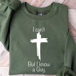 May include: A green sweatshirt with a white cross and the text "I can't But I know a Guy."