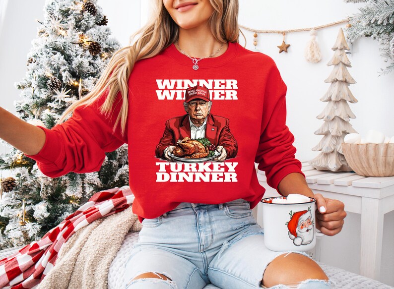 May include: Red Christmas sweater with a white graphic of a person holding a turkey dinner. The text on the sweater reads "Winner Winner Turkey Dinner".