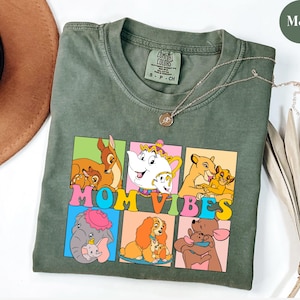 May include: A green t-shirt with a graphic of Disney characters and the text "MOM VIBES". The characters include Bambi, Lady and the Tramp, Dumbo, and Simba.