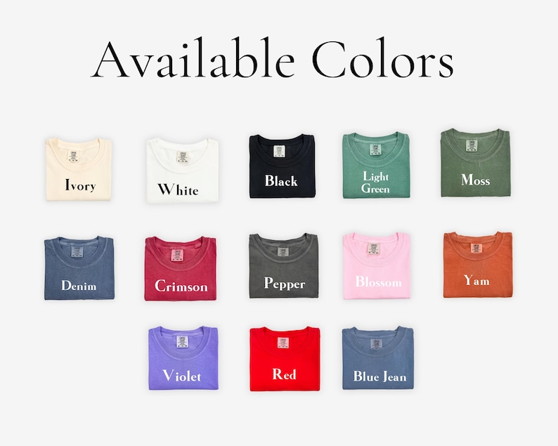 May include: A selection of 13 folded t-shirts in various colors, including ivory, white, black, light green, moss, denim, crimson, pepper, blossom, yam, violet, red, and blue jean. The text "Available Colors" is displayed above the t-shirts.