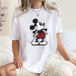 May include: White t-shirt with a black and white cartoon image of Mickey Mouse wearing red shorts.