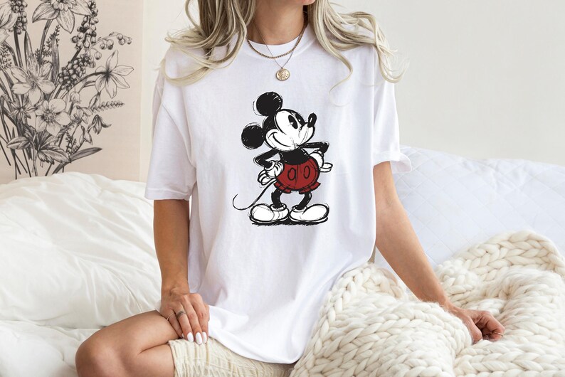 May include: White t-shirt with a black and white cartoon image of Mickey Mouse wearing red shorts.