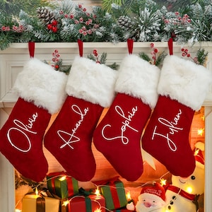 May include: Four red Christmas stockings with white faux fur trim and personalized names: Olivia, Amanda, Sophia, and Julian.
