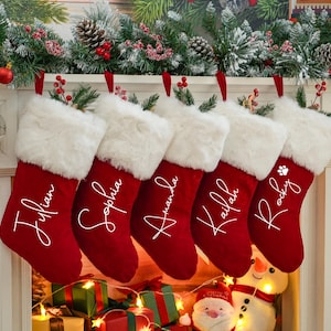 May include: Five red velvet Christmas stockings with white faux fur trim hanging on a fireplace mantel. The stockings are personalized with the names "Julian", "Sophia", "Amanda", "Kailan", and "Rocky".