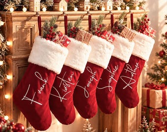May include: Five red velvet Christmas stockings with white faux fur cuffs, each personalised with white cursive text reading Frank, Kirsten, Joseph, Sophie, and Arthur. Each stocking is filled with small gift boxes, pine sprigs, and red berries.