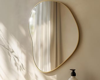 Grote organische wandspiegel met slank goudkleurig frame, asymmetrische blikvanger voor de badkamer.