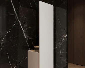 May include: A vertical white rectangular panel with a matching white storage box attached to the lower section. The unit is mounted against a dark black marble wall with prominent white veining, creating a high-contrast visual display.