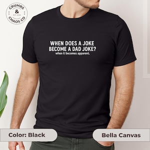 May include: Black t-shirt with the text "WHEN DOES A JOKE BECOME A DAD JOKE? when it becomes apparent." The shirt also features a small logo that says "CRUMBS & CHAOS CO EST. 2025". The shirt is made by Bella Canvas.