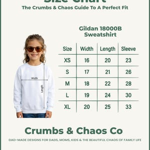 Puede incluir: Una sudadera blanca Gildan 18000B con una tabla de tallas. La tabla muestra medidas para las tallas XS a XL, incluyendo ancho, largo y largo de manga en cent&iacute;metros. El texto "Crumbs & Chaos Co" est&aacute; en la parte inferior.