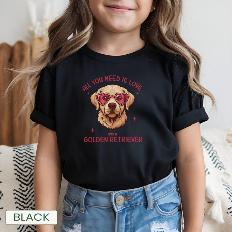 Puede incluir: Camiseta negra con un Golden Retriever con gafas de sol en forma de coraz&oacute;n. El texto dice "ALL YOU NEED IS LOVE AND A GOLDEN RETRIEVER" en rojo. La palabra "BLACK" est&aacute; en la parte inferior.