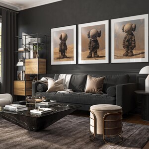 Peut inclure: Un salon gris foncé avec un canapé noir, une table basse noire et un pouf beige. Trois impressions encadrées de figures grises sur fond de désert sont accrochées au mur. Une lampe se trouve sur une petite table dans le coin.