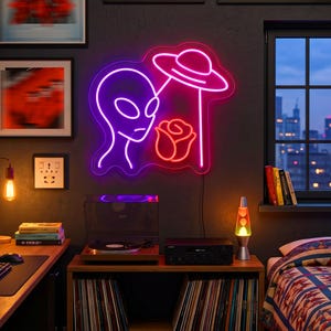 May include: A neon wall sign featuring a purple alien head outline next to a red rose and a pink UFO silhouette. The light emits a vibrant glow against the dark wall, creating a distinct contrast between the purple, red, and pink neon tubing.