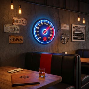 Peut inclure: D&eacute;cor mural avec un compteur de vitesse r&eacute;tro &eacute;clair&eacute; au n&eacute;on bleu et rouge, sur un mur gris textur&eacute;. Des plaques d'immatriculation vintage et une photo de voiture encadr&eacute;e compl&egrave;tent le style. Une table en bois avec un menu en cuir et un verre de liquide ambr&eacute; au premier plan.