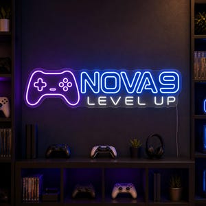 May include: A rectangular neon sign featuring a purple outline of a game controller on the left and the blue text NOVA 9 with the white text LEVEL UP underneath. The sign is mounted on a dark wall above a shelf containing various gaming accessories.