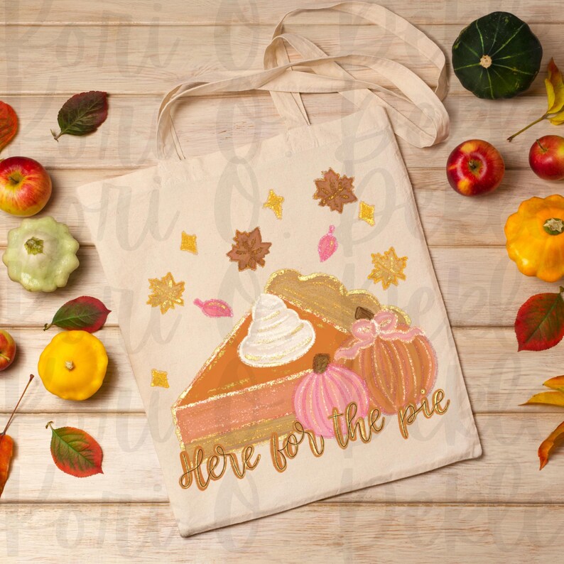 Peut inclure: Un sac fourre-tout beige avec un motif peint &agrave; la main d'une part de tarte &agrave; la citrouille avec de la cr&egrave;me fouett&eacute;e et deux citrouilles. Le texte "Here for the pie" est &eacute;crit en paillettes dor&eacute;es sur le sac.
