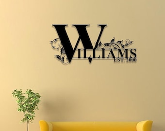 May include: Black metal wall decor with a large letter W and the word "WILLIAMS" with the text "EST. 2000" below. The decor is mounted on a light yellow wall above a yellow couch.