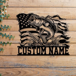 May include: Black metal silhouette of a bass fish leaping from the water with an American flag in the background. The text "CUSTOM NAME" is below the fish.