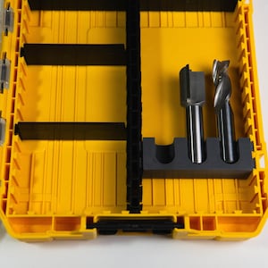 May include: A yellow and black plastic tool box with two metal drill bits inside. The drill bits are in a black foam holder.
