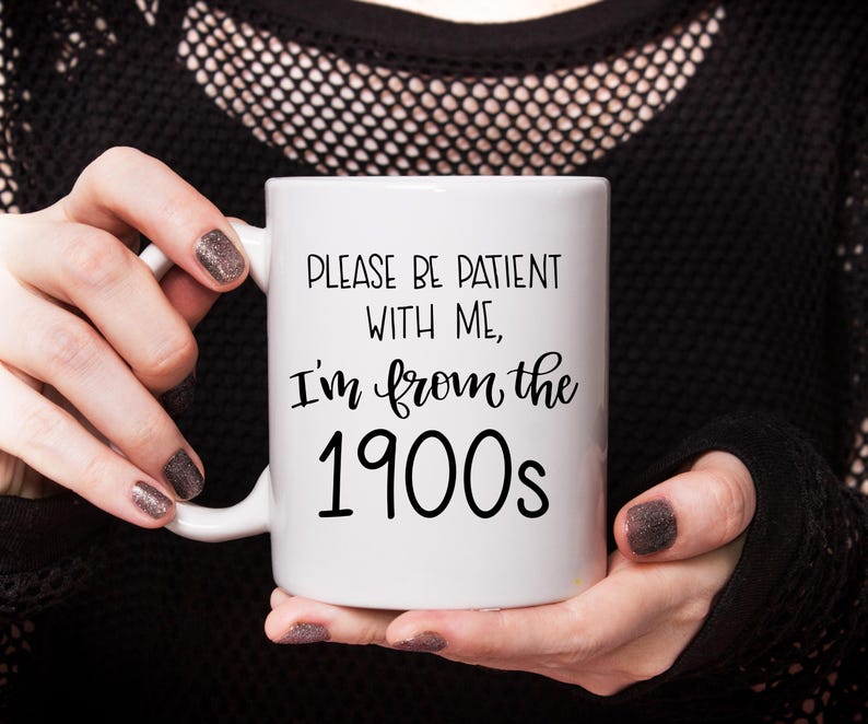 May include: White ceramic mug with black text that reads "Please be patient with me, I'm from the 1900s".