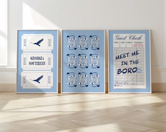 May include: Three framed prints with a blue and white color scheme. The left print features a ticket with the text "Georgia Southern" and a bird graphic. The center print features a repeating pattern of blue and white geometric shapes. The right print features a vintage-style receipt with the text "Meet Me In The Boro".