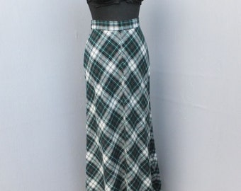May include: A long, black and white plaid skirt with a green and white plaid pattern. The skirt is made of a thick, woven fabric and has a simple, straight silhouette.