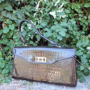 May include: A brown crocodile-embossed handbag with a gold-toned clasp.