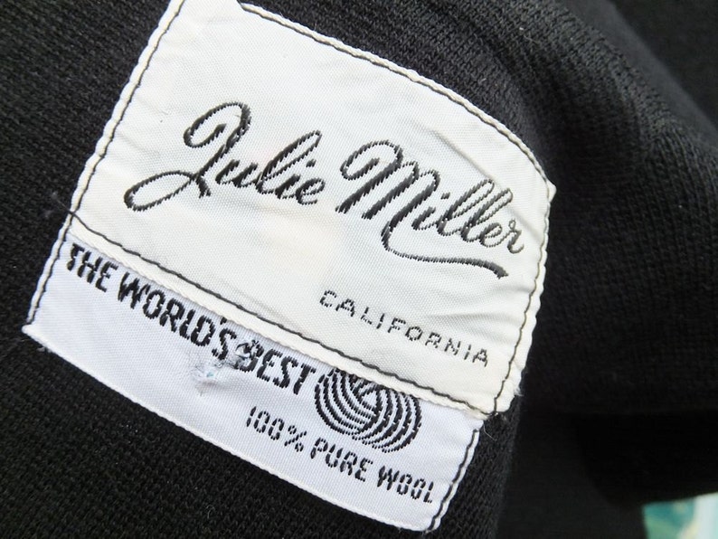 Puede incluir: Etiqueta blanca con texto negro que dice "Julie Miller California The World's Best 100% Pure Wool".