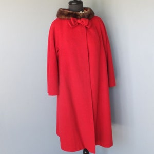 May include: A red wool coat with a brown fur collar and a bow at the neckline.