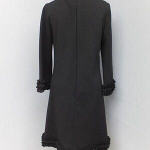 Puede incluir: Un vestido negro con un dobladillo y mangas con volantes. El vestido tiene un dise&ntilde;o simple y elegante y es perfecto para una ocasi&oacute;n especial.