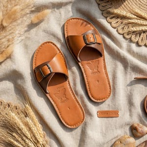 Handmade Moroccan leather buckle sandals for women styled in boho natural setting, genuine leather flat slide summer shoes with minimalist artisan design