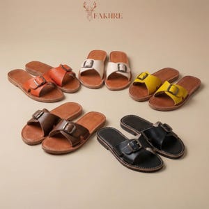 Multiple color handmade Moroccan leather buckle sandals for women, genuine leather boho flat slide summer shoes, minimalist artisan comfort sandals photographed in warm natural styled setting
