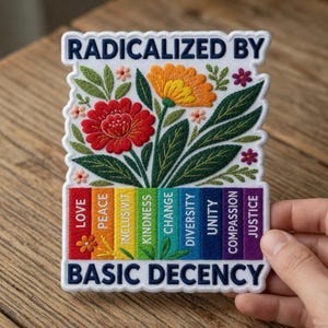 May include: Embroidered patch with the text "RADICALIZED BY BASIC DECENCY." Features a floral design with a red and orange flower, green leaves, and a rainbow of words: LOVE, PEACE, INCLUSIVITY, KINDNESS, CHANGE, DIVERSITY, UNITY, COMPASSION, JUSTICE.
