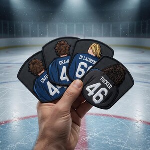 May include: A hand displaying four hockey jersey patches. The patches are black with the backs of players in blue and black jerseys. Each patch has a name and number, including "GRAHAM 4", "DI LAUREN 61", and "TUCKER 46".