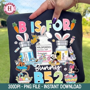 May include: Black sweatshirt with the words "B IS FOR" in colorful letters, with cartoon bunny ears and images of Disney characters. The design includes the text "Bunny B52" and medical vials.