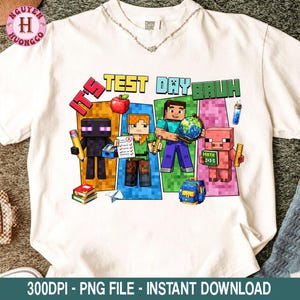 Puede incluir: Camiseta blanca con un gr&aacute;fico colorido que presenta personajes pixelados y el texto "IT'S TEST DAY BRUH". El dise&ntilde;o incluye una manzana, libros, un globo terr&aacute;queo y una mochila. La camiseta es de la marca Comfort Colors.