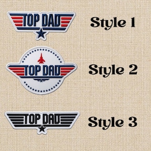 May include: Three embroidered patches with the text "TOP DAD" in different styles. Style 1 is blue, red, and white with a star. Style 2 is white with a red jet and stars. Style 3 is black and white with a star. The text "Style 1", "Style 2", and "Style 3" are also visible.