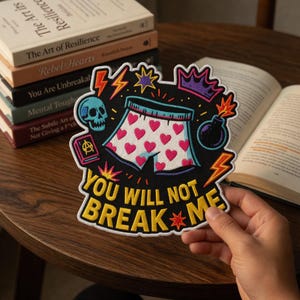 Może przedstawiać: Haftowana naszywka z napisem "YOU WILL NOT BREAK ME". Naszywka przedstawia białe bokserki z różowymi sercami, czaszkę, koronę i bombę. Błyskawice i gwiazdy otaczają wzór.
