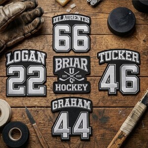 Könnte beinhalten: Eine Sammlung von schwarz-weißen Hockey-Patches mit Spielernamen und -nummern. Die Patches enthalten Namen wie "Logan", "Tucker" und "Graham" mit Nummern wie 22, 46 und 44. Ein Hockeypuck und ein Handschuh sind ebenfalls zu sehen.