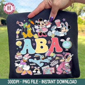 May include: Black graphic sweatshirt featuring cartoon characters, including Mickey and Minnie Mouse, and the text "ABA". The design includes colorful illustrations of eggs, carrots, and other elements.