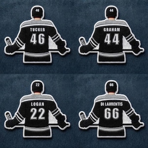 May include: Four embroidered hockey jersey patches. Each patch features a black jersey with white and grey accents, a player's name, and a number. The names are Tucker, Graham, Logan, and Di Laurentis. The numbers are 46, 44, 22, and 66.