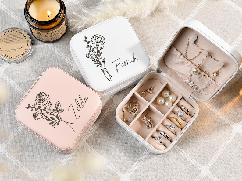 May include: Two white and pink square jewelry boxes with floral designs and personalized names "Farrah" and "Zelda". The white box has a compartment for rings and earrings.