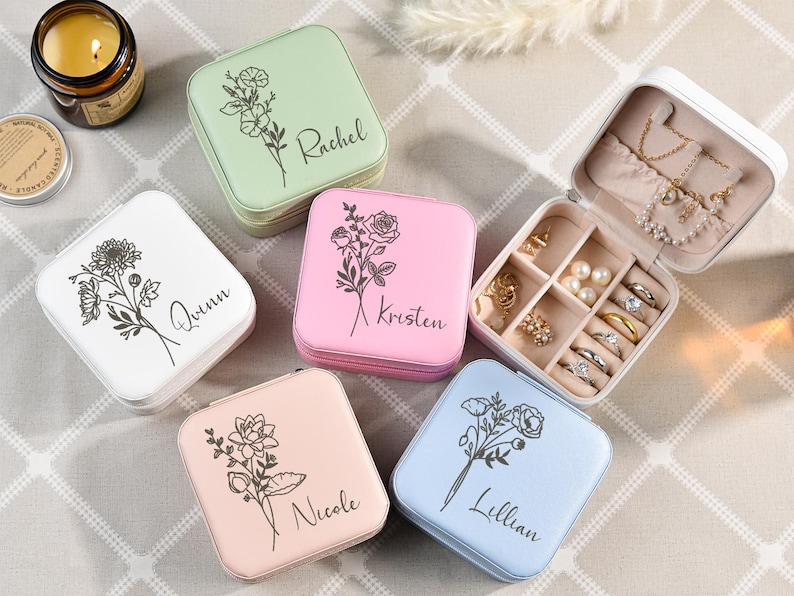 May include: Five small square jewelry boxes with floral designs and personalized names: Rachel, Quinn, Kristen, Nicole, and Lillian. Each box has a different color: green, white, pink, light pink, and light blue.
