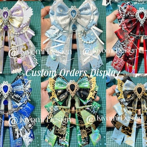 May include: A display of custom-made decorative bows in various colors, including purple, blue, red, green, and gold. Each bow features intricate designs, ribbons, and embellishments, with the text "Custom Orders Display" visible.