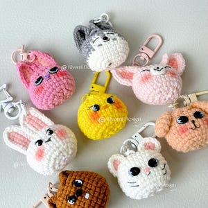 May include: A collection of handmade crochet animal keychains in various colors, including pink, white, yellow, gray, and brown. Each keychain features a different animal face, such as a bunny, cat, and dog, with a metal clasp for attachment.