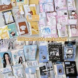 May include: A selection of packaged items in various colours and designs. The packages feature images of people, text, and decorative elements. The text "Different cute packaging!" is visible. The packages are tied with ribbons and bows.
