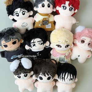 May include: A collection of plush dolls with various hairstyles and outfits. The dolls have large eyes and are in a variety of colors, including black, brown, red, and blonde. Some dolls have accessories like sunglasses or overalls. The text "@kivomi Design" is visible.