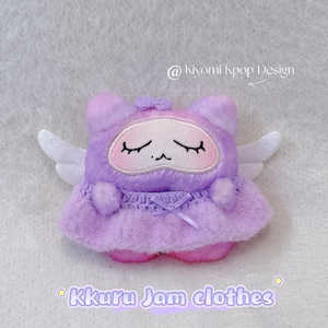 May include: A plush toy in the shape of a purple cat with closed eyes, white wings, and a small bow. The toy is wearing a purple dress with a bow. Text on the image reads "Kkuru Jam clothes" and "@kiyomi kpop Design".