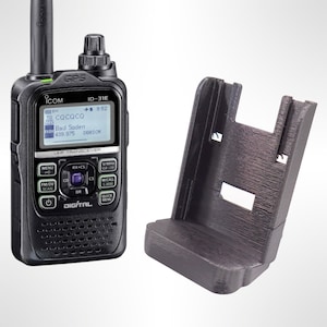 May include: A black handheld radio with a digital display showing the text "CQCQCQ" and "Bad Soden" with a number. The radio is sitting on a black charging stand.